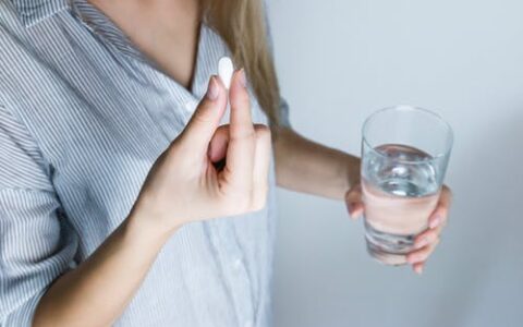 Woman holding pill and water