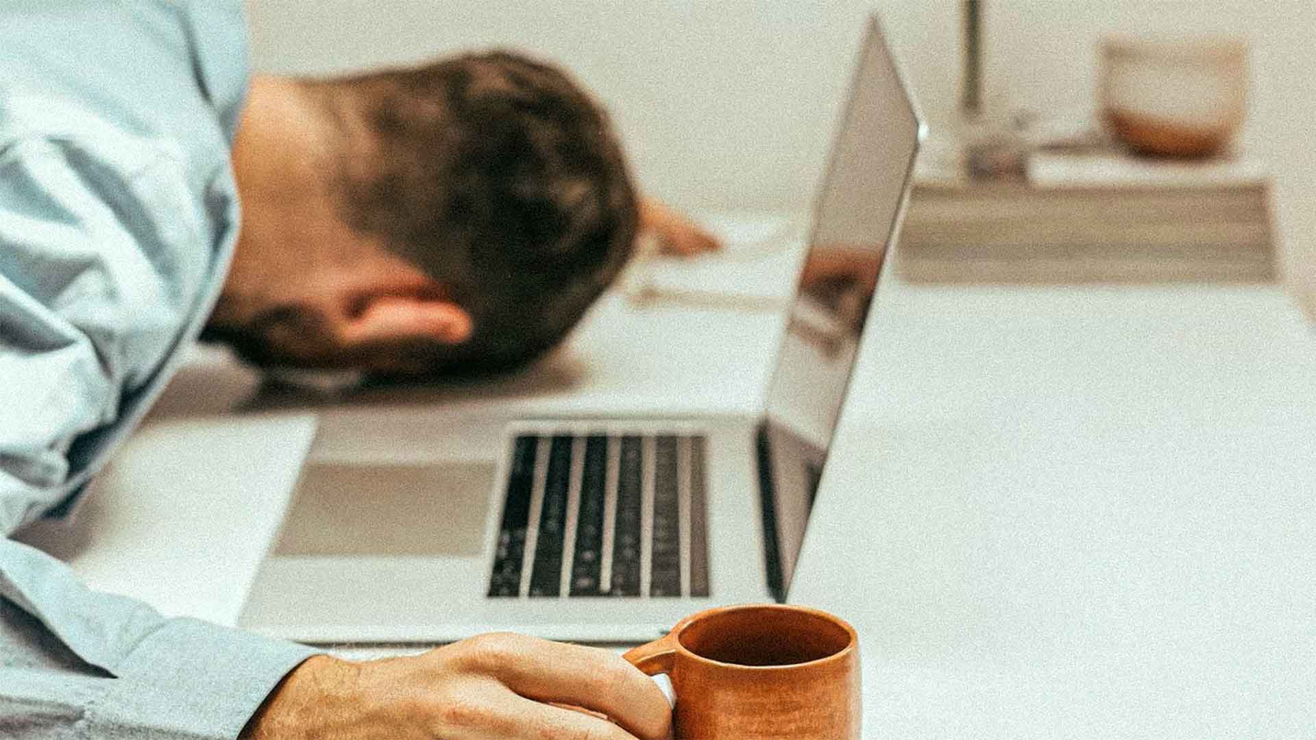 man sleeping next to his laptop