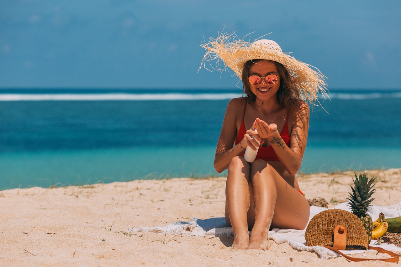 woman putting sun screen on at beach