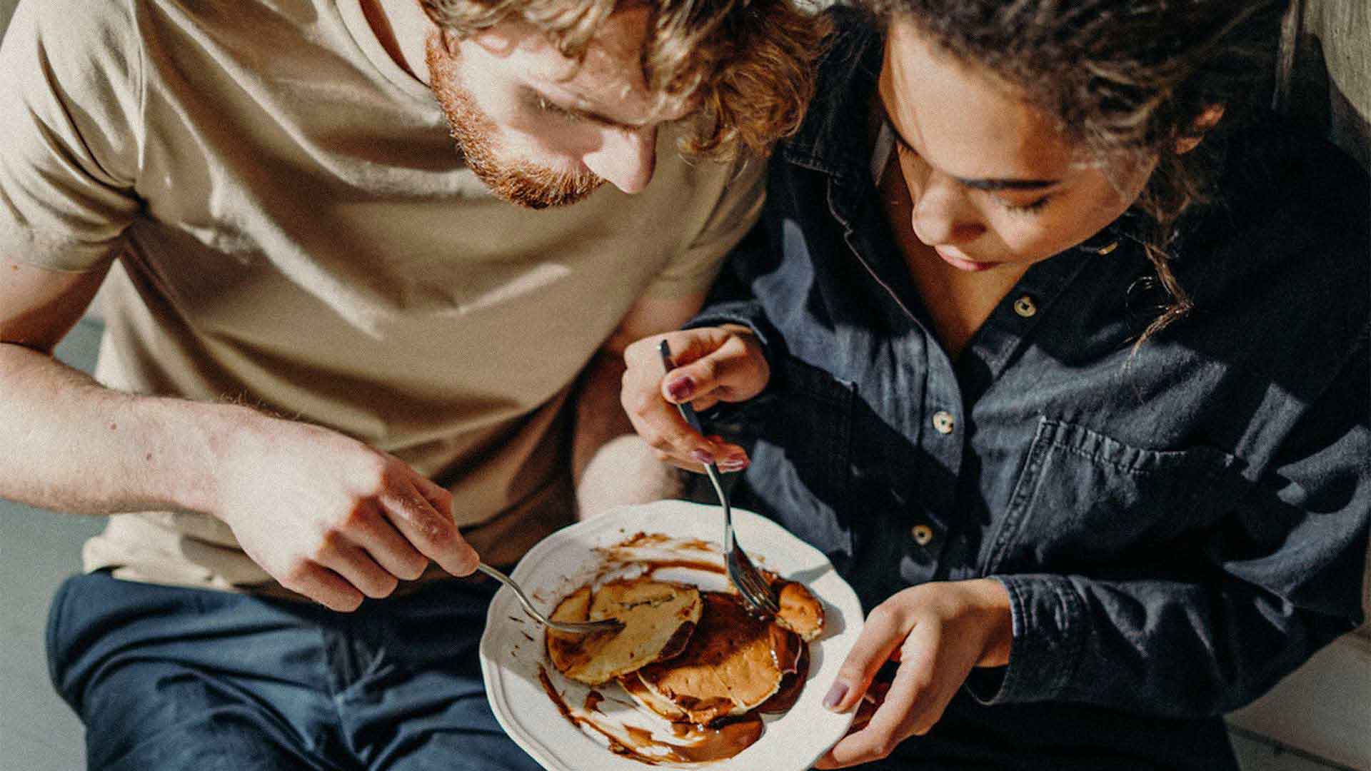 two people sharing food off a plate